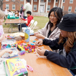 Hazel Lam-Mackintosh and Harper Thaden (left) make bead bracelets with UMW students Jenny Vuong and Boramy Meng. Photo by Suzanne Carr Rossi.