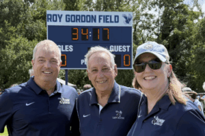 Coach Roy Gordon (center) poses for a photo with Director of Athletics Patrick Catullo ’95 (left) and Vice President for Advancement and Alumni Engagement Katie Turcotte (right) during a ceremony held Sunday to name the Roy Gordon Field. Photo courtesy of Katie Turcotte.
