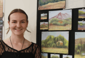 Senior art major Madison Hinton poses beside the sketches and paintings she created during a summer program in the South of France. The trip was fully funded, thanks to the Rosalie Chauncey Memorial Scholarship in Studio Art. Photo by Karen Pearlman.