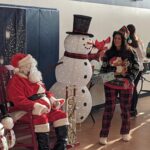 Local kids participating in Head Start classes get a visit from Santa and from UMW student "elves" delivering gift boxes.