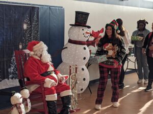 Local kids participating in Head Start classes get a visit from Santa and from UMW student "elves" delivering gift boxes.