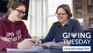 Photo of a professor and student at a table with info on Giving Tuesday. 