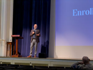 Image of an adult male on stage giving a speech