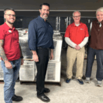Photo of four adult men with air conditioning units