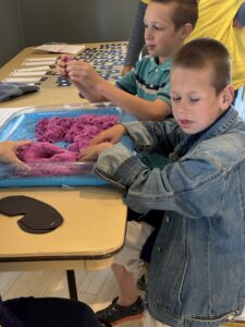 Young boy experiencing purple kinetic sand.