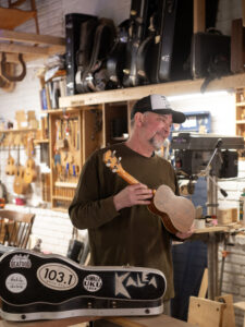 photo of a man named Larry Kinkle holding an instrument made of wood
