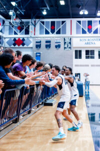 Men's basketball team members celebrating with fans in the stands