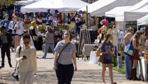 people walk and shop at various vendors positioned on campus walk 