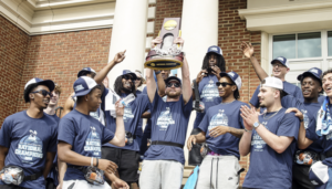 Basketball players stand on the steps of Anderson Center with a trophy