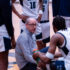 Photo of Coach Kahn kneeling with players in a huddle on the court