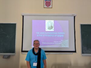 Professor Al-Tikriti stands in a classroom in front of of a presentation slide