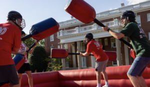 Students dressed in red and green play inside a bouncy ring during a playful competition on Devil-Goat Day