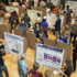 An auditorium full of students displaying posters to attendees