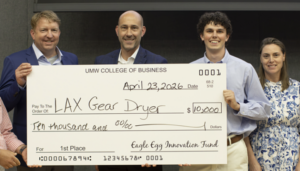 the winning student holds an oversized check accompanied by the judges