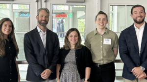 Five UMW College of Business graduates stand together in Woodard Hall