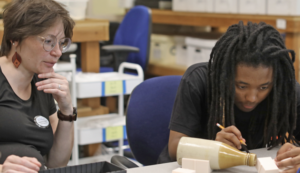 Student Kai Bryant at a desk taking direction from Professor Parker