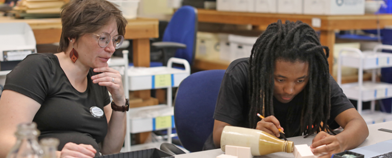 Student Kai Bryant at a desk taking direction from Professor Parker