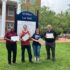 Four people stand with laptops in front of Lee Hall on UMW campus