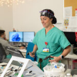 Sabrina Elliott in green scrubs practices a surgery technique