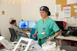 Sabrina Elliott in green scrubs practices a surgery technique