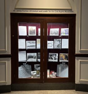 Display of memorabilia on glass shelf inside a display case with red velvet backing