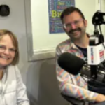 woman and man sit behind microphones at a table
