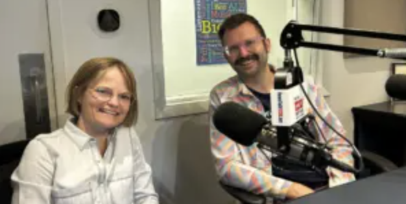 woman and man sit behind microphones at a table