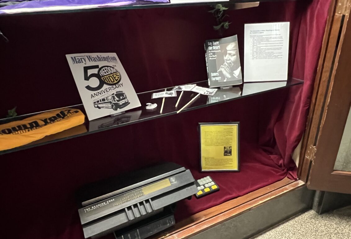 Display of memorabilia on glass shelf inside a display case with red velvet backing