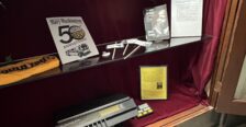 Display of memorabilia on glass shelf inside a display case with red velvet backing