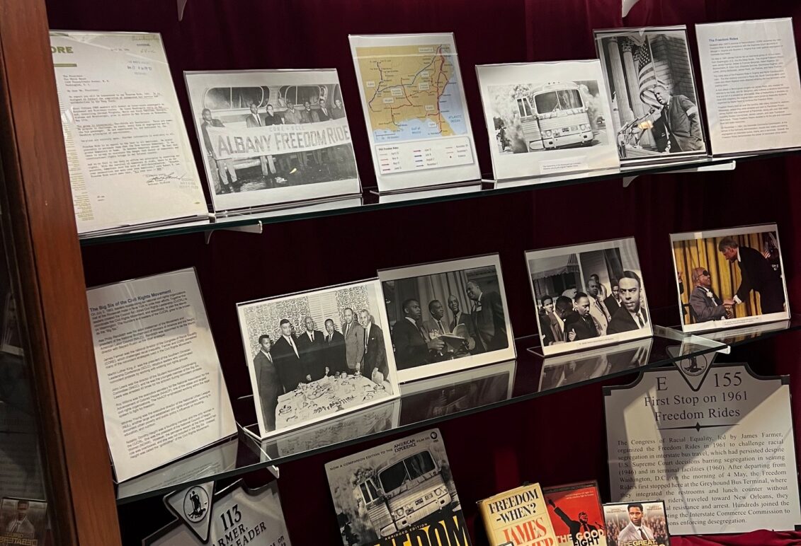 Display of memorabilia on glass shelf inside a display case with red velvet backing