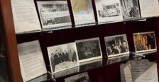 Display of memorabilia on glass shelf inside a display case with red velvet backing