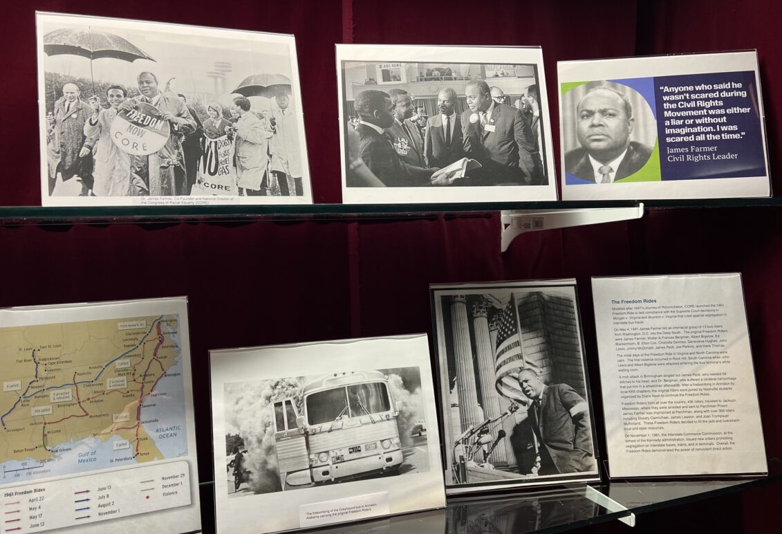 Display of memorabilia on glass shelf inside a display case with red velvet backing