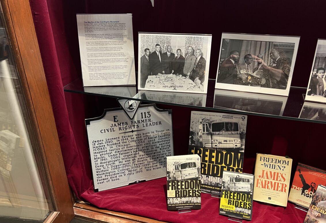 Display of memorabilia on glass shelf inside a display case with red velvet backing