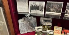 Display of memorabilia on glass shelf inside a display case with red velvet backing