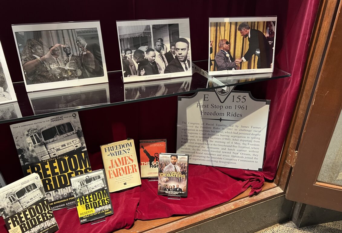 Display of memorabilia on glass shelf inside a display case with red velvet backing