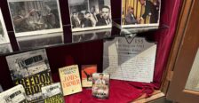 Display of memorabilia on glass shelf inside a display case with red velvet backing