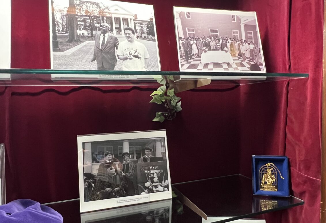 Display of memorabilia, likes books and photos, on glass shelf inside a case with red velvet backing