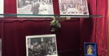Display of memorabilia, likes books and photos, on glass shelf inside a case with red velvet backing