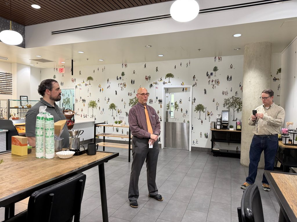 Three people stand in a coffee shop