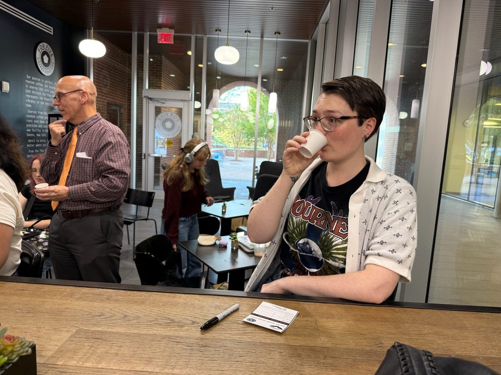 A person drinks coffee from a small cup