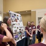 students stand next to a poster on an easel