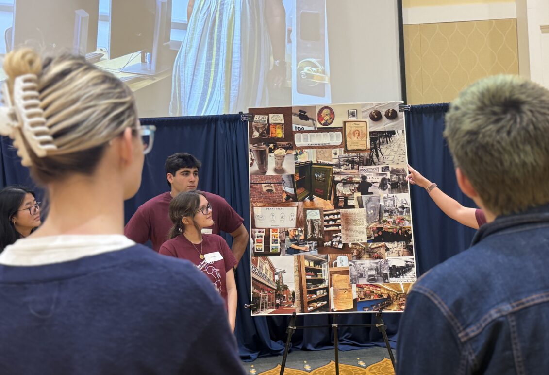 students stand next to a poster on an easel
