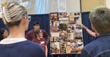 students stand next to a poster on an easel
