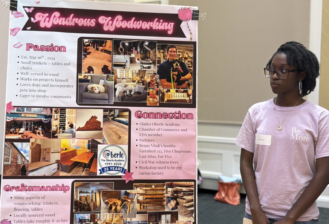 a student stands next to a poster on an easel
