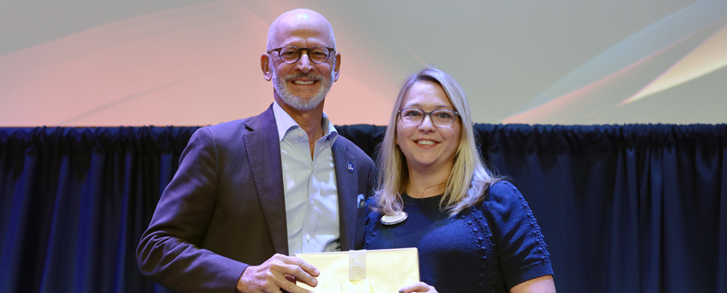 Male and female stand together holding a certificate